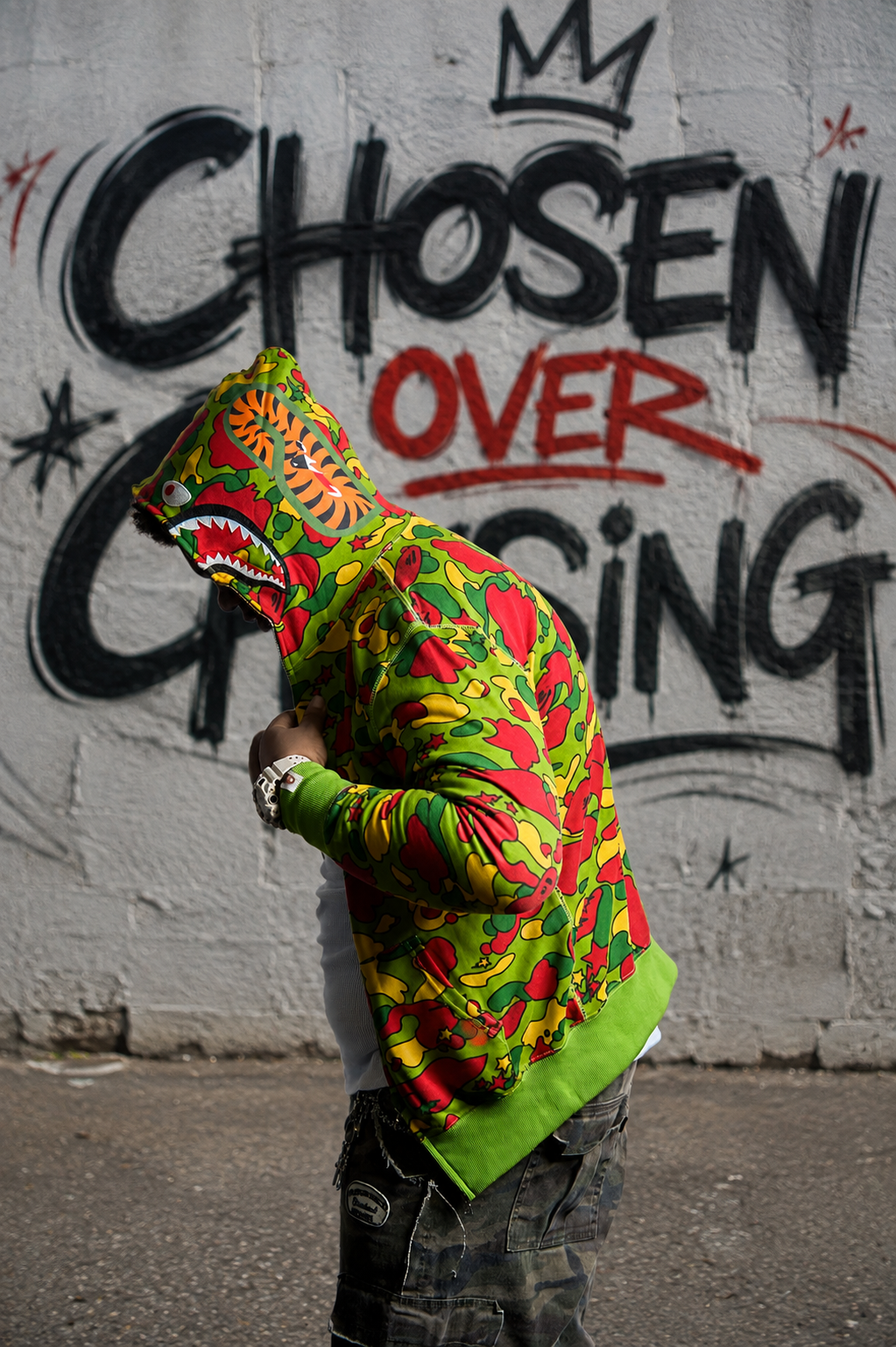 YO.G.I walking past a wall painted with the words Chosen Over Chasing